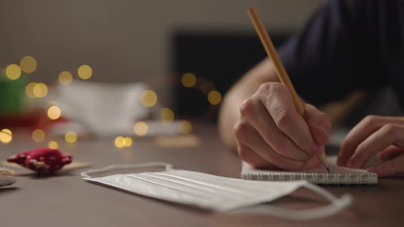 Slow Motion Orbit Shot Closeup Man Writes Shopping List Notepad Pencil Under Warm Light Evening