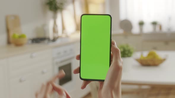 Back View of Woman at Kitchen Room Sitting on a Chair Using Phone With Green Mockup Screen Chroma