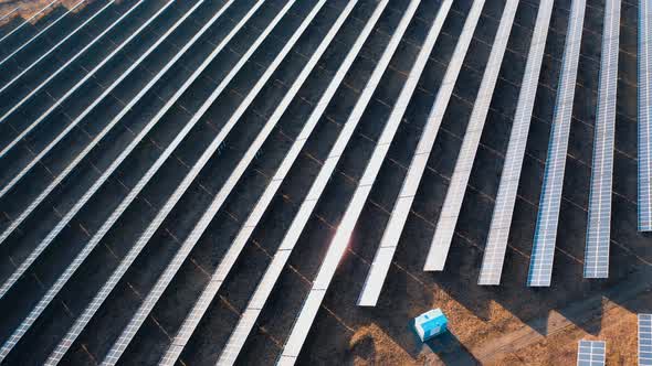 Sunset aerial view of solar panels stand in a row in the fields.