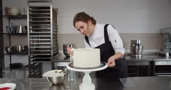 A Professional Confectioner Decorates a Holiday Cake with Cream in a Confectionery Shop