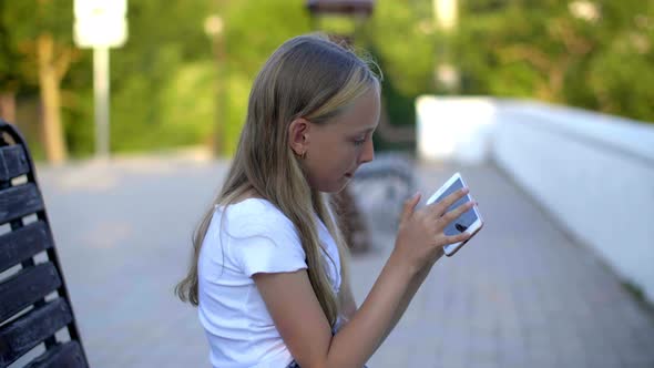 Cute Focused Teen Girl Using Smartphone Outdoors