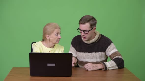 Young Man Teaching Senior Businesswoman How To Use Laptop