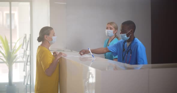 Senior Woman in Safety Mask Getting Doctor Appointment at Hospital Reception