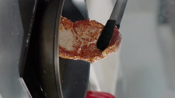 Vertical Video Professional Chef Cooking Pork Steak in Frying Pan on Stove