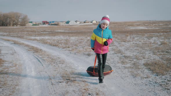 Young Girl Riding on Inflatable Snow Tube From a Hill.