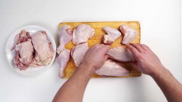 Men's Hands Lay Out a Butchered Carcass of Raw Chicken on a Wooden Cutting Board