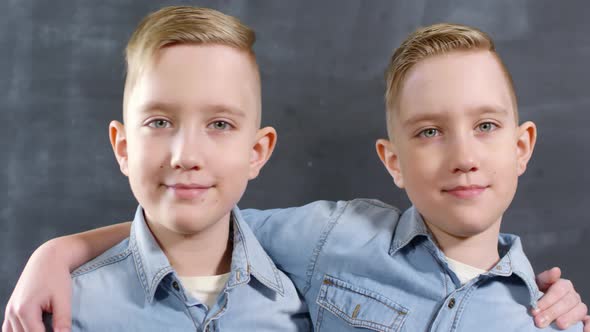 Caucasian Twin Brothers Hugging and Posing against Blackboard alt