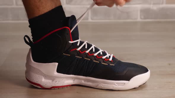 A Closeup of a Man's Hands Tying the White Laces of His Basketball Sneakers