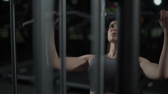 Young Sporty Female in the Gym Lifting Blocks on Blocks Machine Strength Training on a Gym Equipment