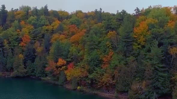 Beautiful aerial dolly shot of hikers travelling along the lake near Gatineau Park at Autumn.