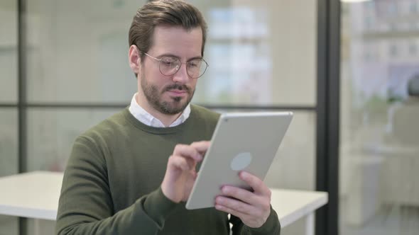 Portrait of Young Businessman Using Tablet in Office