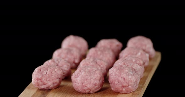 Raw Meatballs on a Wooden Cutting Board Slowly Rotate. 