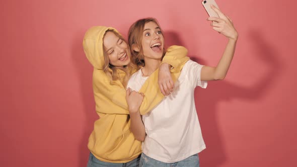 Two young beautiful smiling hipster girls in trendy summer clothes