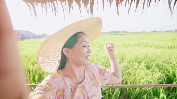 Adult woman making video call showing large rice production field.