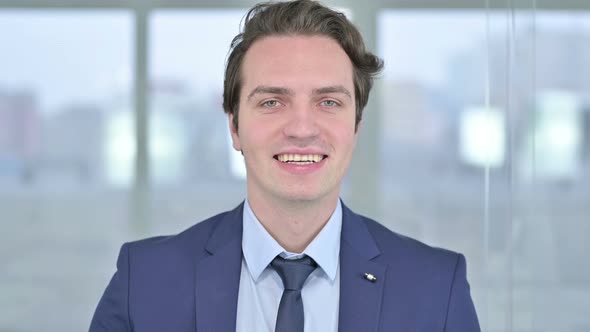 Portrait of Cheerful Young Businessman Waving at the Camera 