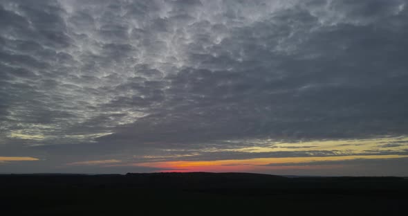 The Sun Sets Over The Horizon Turning The Clouds Into Shades Of Red