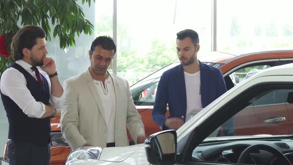 Three Male Friends Examining Car for Sale at the Dealership