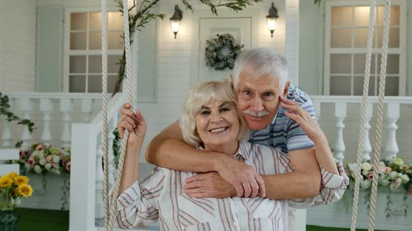 Senior Couple Together in Front Yard at Home. Man Swinging and Hugging Woman. Happy Mature Family