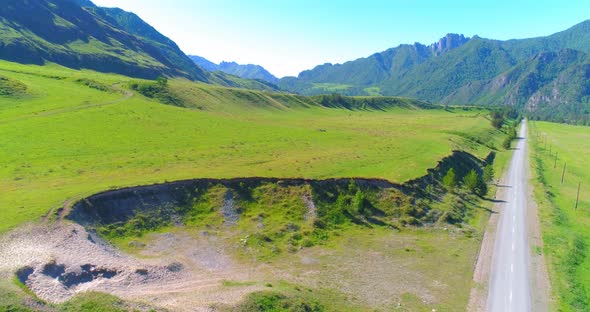 Aerial Rural Mountain Road and Meadow at Sunny Summer Morning. Asphalt Highway and River.