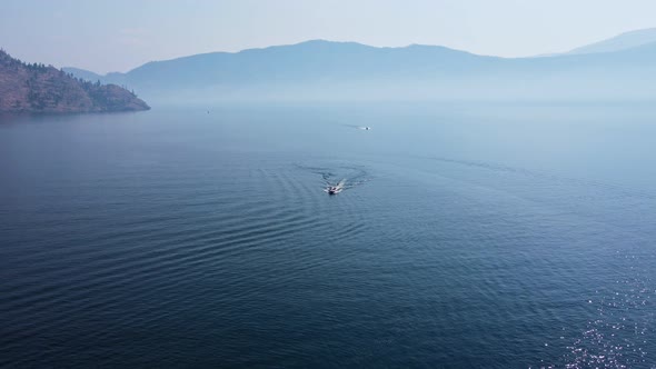 Two speed boats driving over deep, blue Okanagan Lake on a hot summer day in Canada. High aerial ped