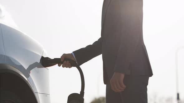 Unrecognizable Businessman Unplugging Electric Car