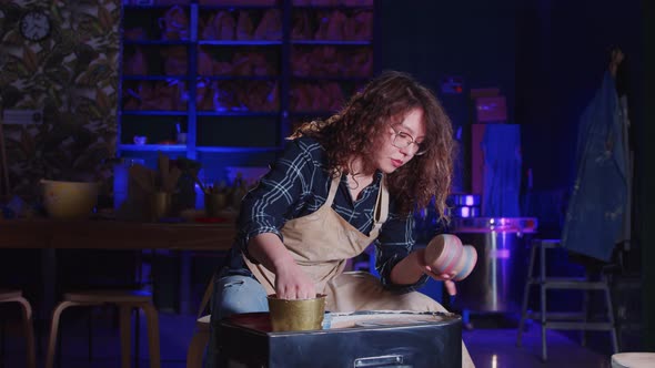Woman with Curly Hair Wiping Out the Bottom of the Fresh New Pot Made Out of Clay