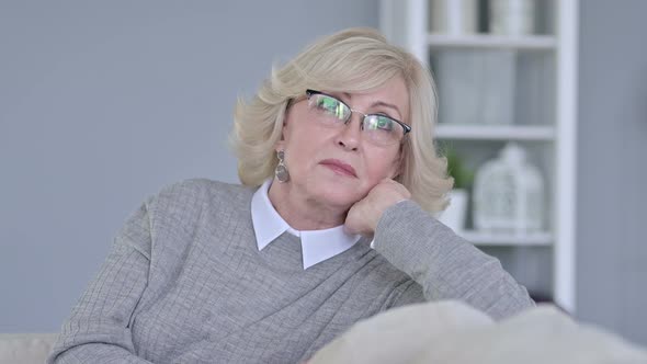 Portrait of Pensive Old Woman Sitting on Sofa and Thinking