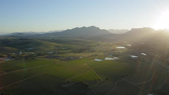 Sun rays sunrise lens flare over vineyard landscape, mountains aerial, Stellenbosch, Longlands