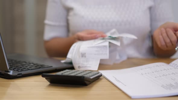 Woman Using Calculator to Calculate Bills at the Table in Office