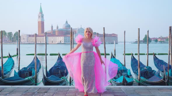 Girl Dressed in Pink in Venice in Front of the Gondolas on the Water