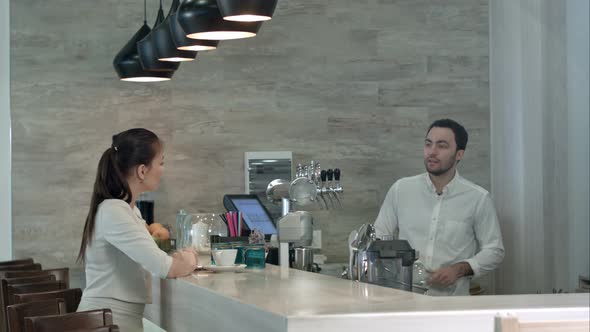 Young Woman Asking Male Barista for a Bill and Paying While Sitting at Cafe Counter