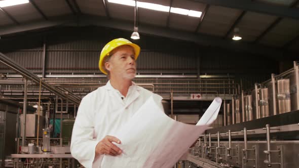 Worker looking at blue print while examining