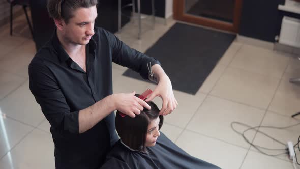 Professional Hairdresser Stylist Makes Professional Hairstyle of Young Woman in Beauty Studio