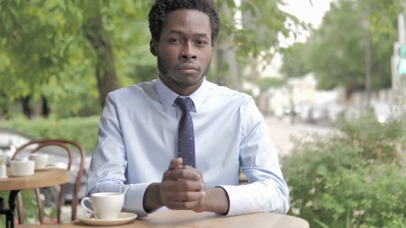 Serious African Businessman Sitting in Outdoor Cafe