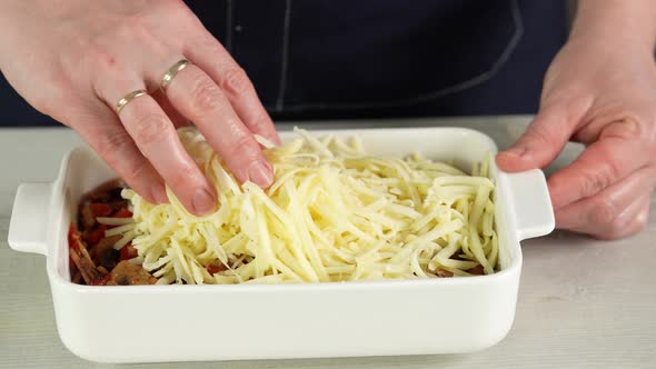 the Chef Lays Out the Cheese on Top of Chopped Ham Paprika and Mushrooms in Ceramic Baking Dish