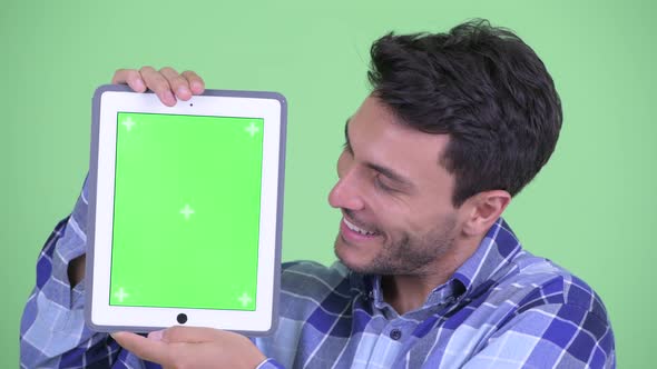 Face of Happy Young Hispanic Man Showing Digital Tablet