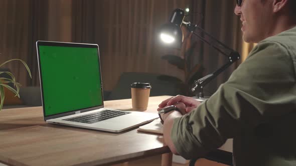 Asian Man Sitting In A Wheelchair While Video Call On Mock Up Green Screen Laptop Computer At Home