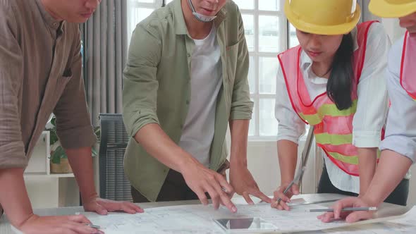 Three Asian Engineers With Helmets Presenting Work On The Tablet To A Man At The Office