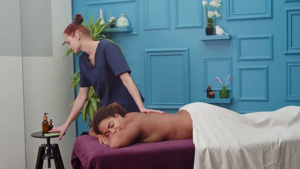 Masseuse Answering to Phone Call While Making Massage to Woman Indoors