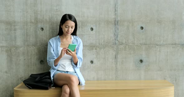 Woman using cellphone and sitting on chair 