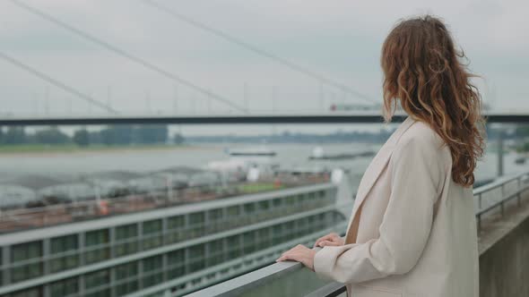 Mature Woman Standing on Bridge and Looking on City River