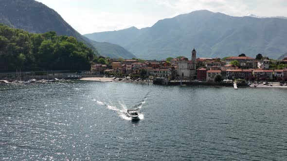 A small boat cruises through Lago Maggiore, Italy, summer day.