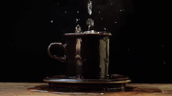 Pouring Water Into An Overflowing Cup - Slow Motion