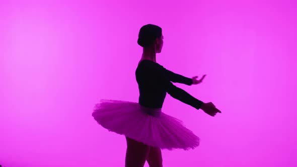 Professional Ballet Dancer Spinning Around in Pink Studio Wall with Violet Light