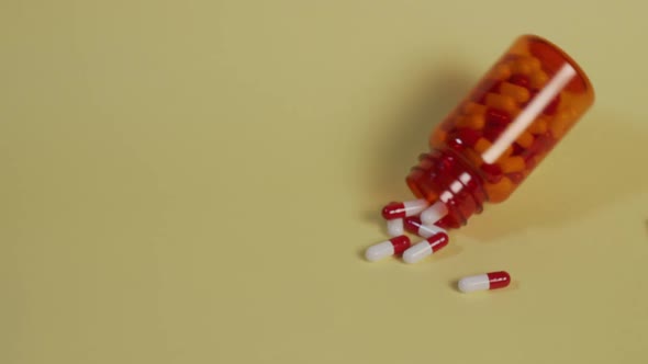 Slow motion high-angle medium shot of a bottle of pills as it falls vertically, bounces, flips over