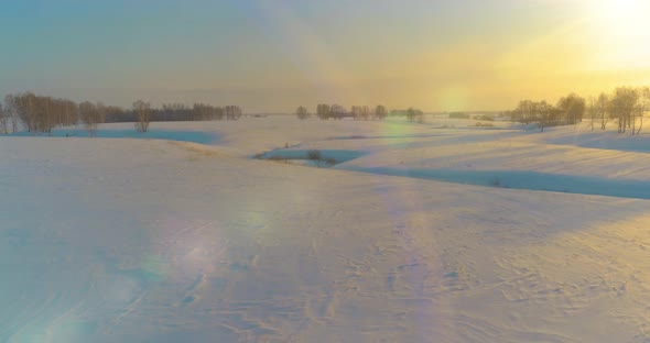 Aerial View of Cold Arctic Field Landscape Trees with Frost Snow Ice River and Sun Rays Over Horizon