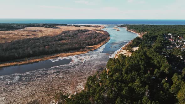 Flight Forward Spring Aerial View Over River Joining Baltic Sea with Melting Ice and Snow