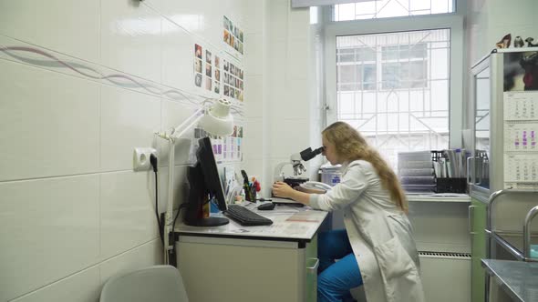 Woman Doctor Looks in a Microscope