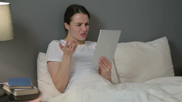 Young Woman Reacting to Loss on Tablet in Bed