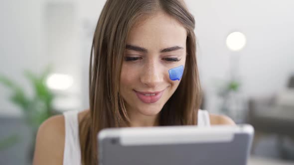 Close-up Portrait of Young Cute Woman Getting Good News From Her Tablet Sitting at Home